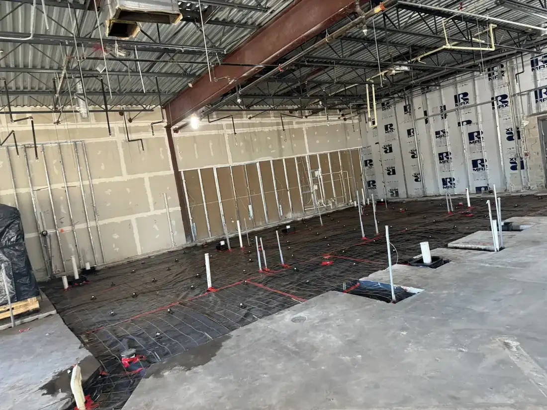Commercial building interior with plumbing stubs and vapor barrier set before the slab pour
