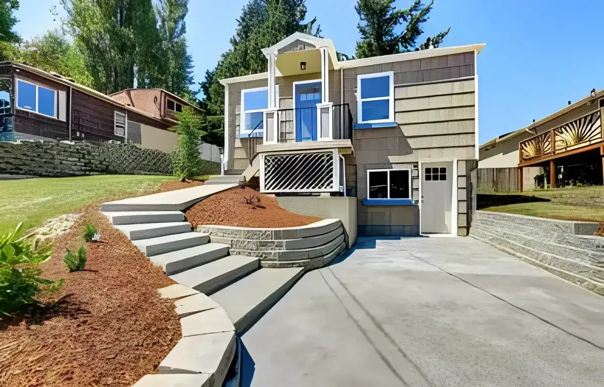 Concrete driveway, entry steps and retaining walls at a two-story house on a slope