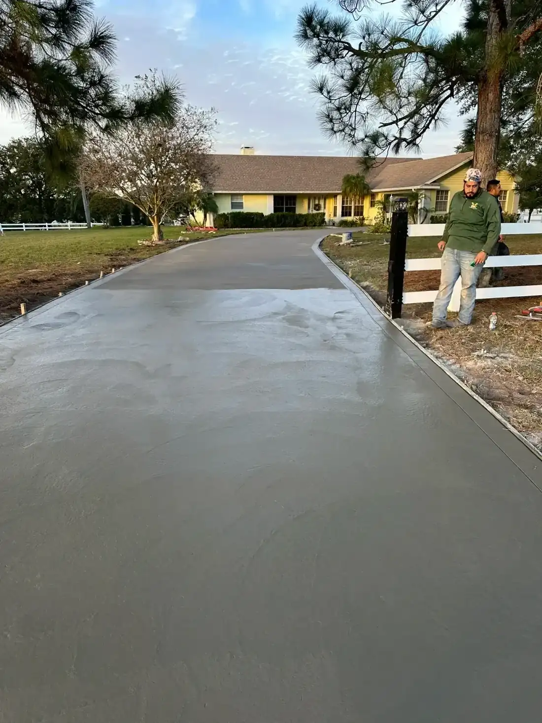 Freshly poured concrete driveway running up to a single-story house