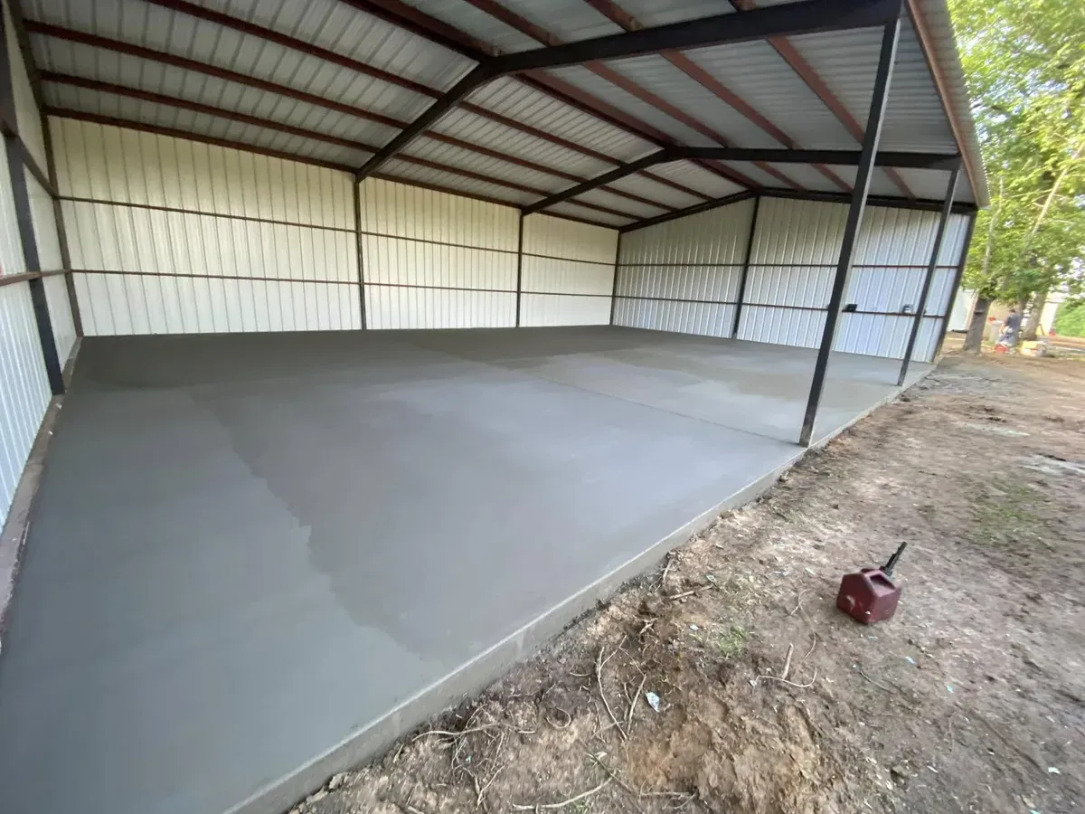New concrete slab under an open-sided metal carport building